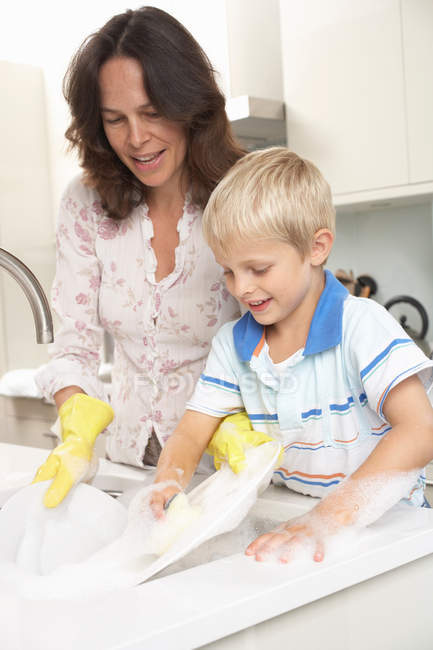 Mutter und Sohn spülen Geschirr in der Küche — Stockfoto