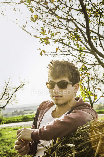 Portrait of young man leaning against haystack — Stock Photo