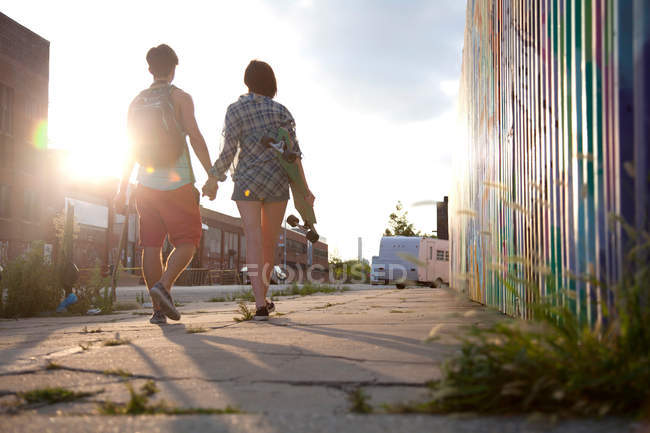 Jeune couple marchant main dans la main, vue arrière — Photo de stock