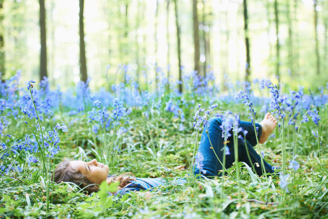 Девушка, лежащая в поле цветов — стоковое фото