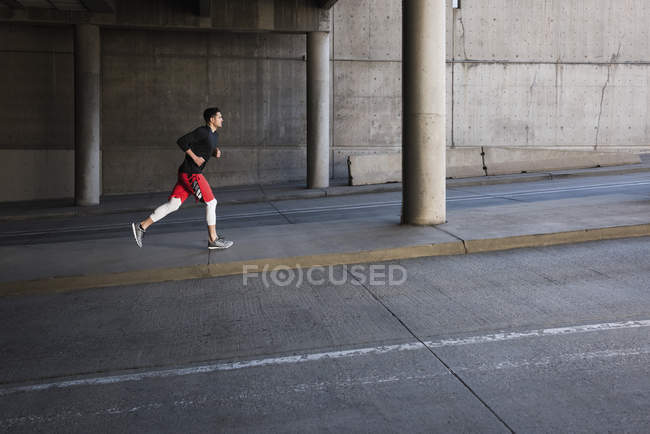 Jovem masculino corredor correndo até cidade underpass — Fotografia de Stock