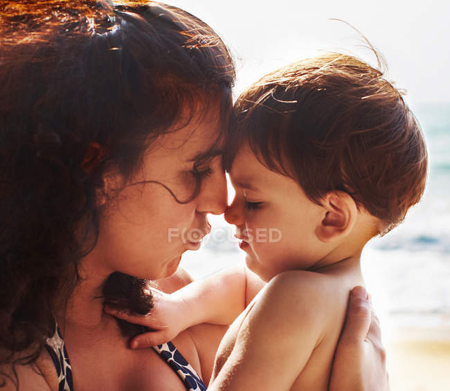Madre y niño pequeño besándose en la playa - foto de stock