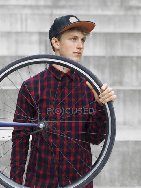 Cycliste urbain portant un pneu devant les marches — Photo de stock