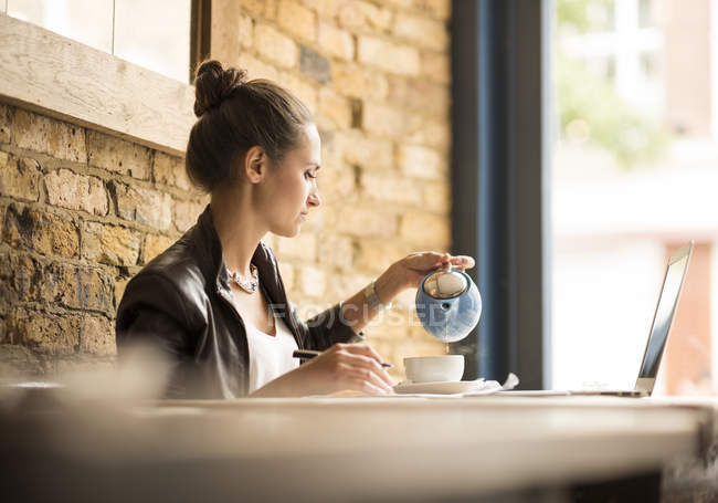 Молодая предпринимательница наливает чай в кафе — стоковое фото