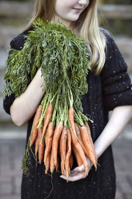 Primer plano de chica con montón de zanahorias - foto de stock