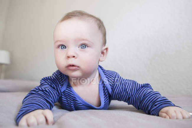 Bambino dagli occhi azzurri strisciare sul letto — Foto stock