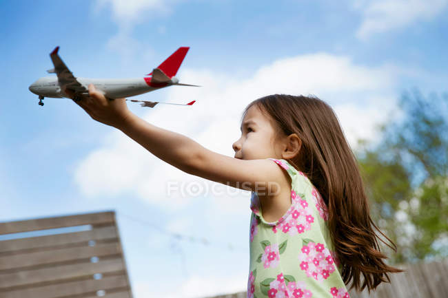 Young girl in garden playing with toy airplane — Stock Photo