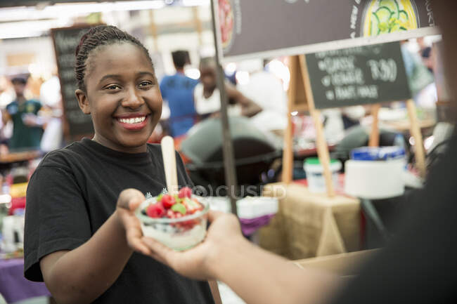 Female stall holder serving fruit salad berries on cooperative food market stall — Stock Photo