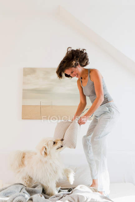 Woman playing with dog in bed — Stock Photo