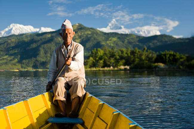 Hombre nepalí remando barco tradicional - foto de stock