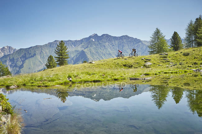 Junges paar mountainbiking bergab, karthaus, val senales, Südtirol, italien — Stockfoto