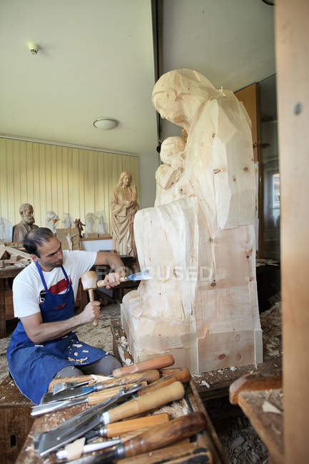 Sculptor chiseling figure from wood — Stock Photo