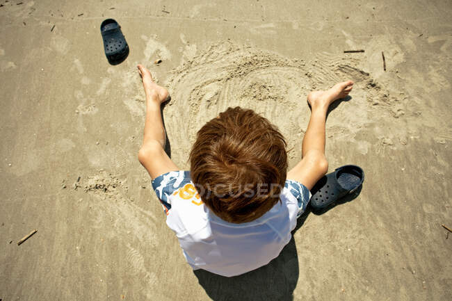 Ragazzo giocare nella sabbia in spiaggia — Foto stock