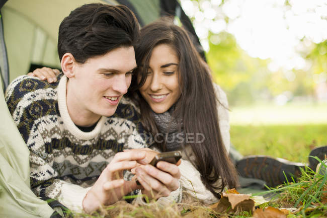 Young couple in tent using smartphone — Stock Photo