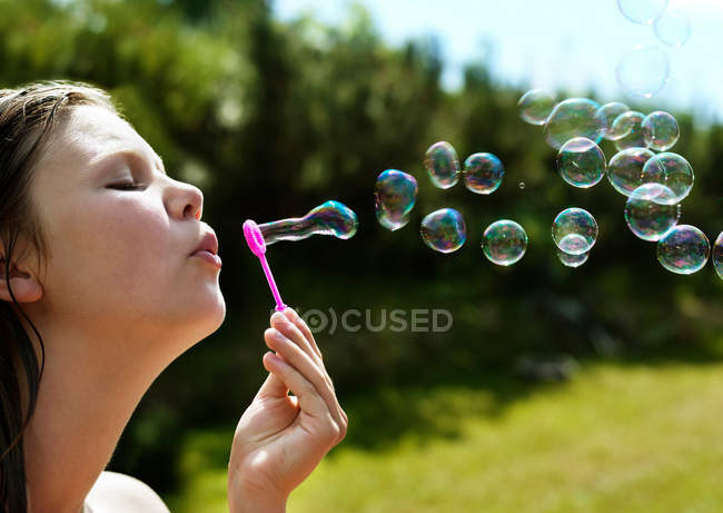 Ragazza che soffia bolle all'aperto, concentrarsi sul primo piano — Foto stock