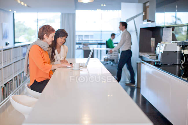 Businesswomen sitting at table looking at laptop — Stock Photo