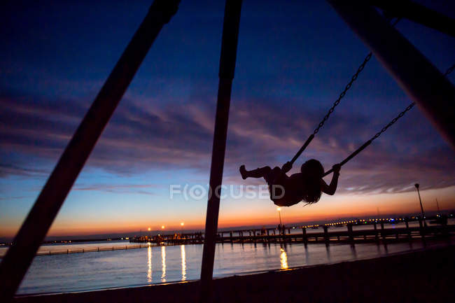 Kind spielt auf Schaukel bei Sonnenuntergang, Park am Meer, neues Trikot, USA — Stockfoto
