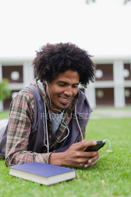 Estudiante escuchando mp3 jugador en la hierba - foto de stock