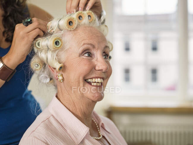 Senior woman with rollers at hairdressers — Stock Photo
