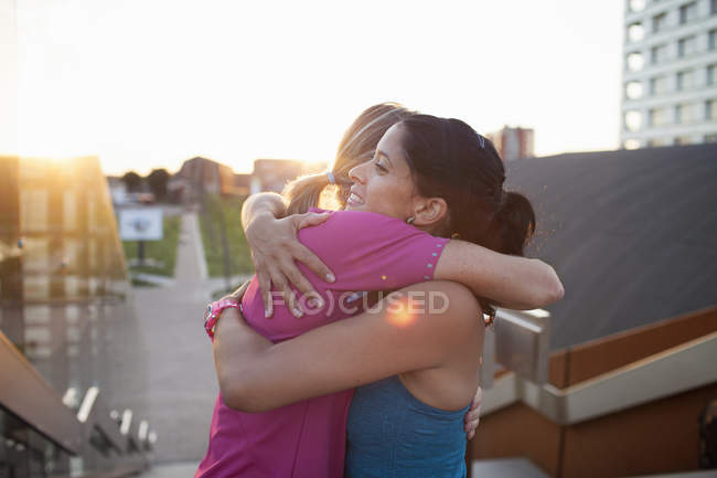 Two women training, hugging on stairway — Stock Photo