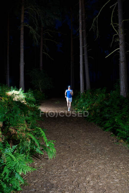 Metà uomo adulto jogging attraverso la foresta di notte — Foto stock