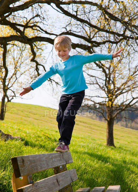 Boy balancing along park bench — Stock Photo