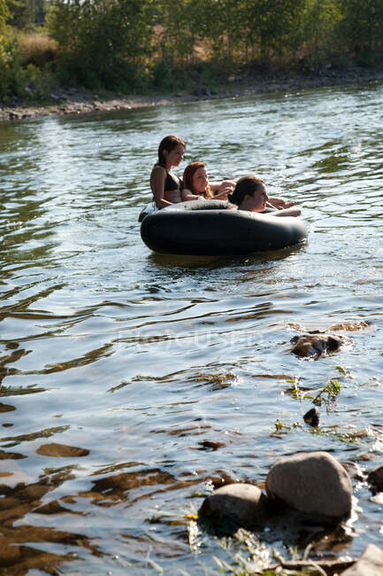 Дамы, плывущие по реке на резиновых платформах — стоковое фото