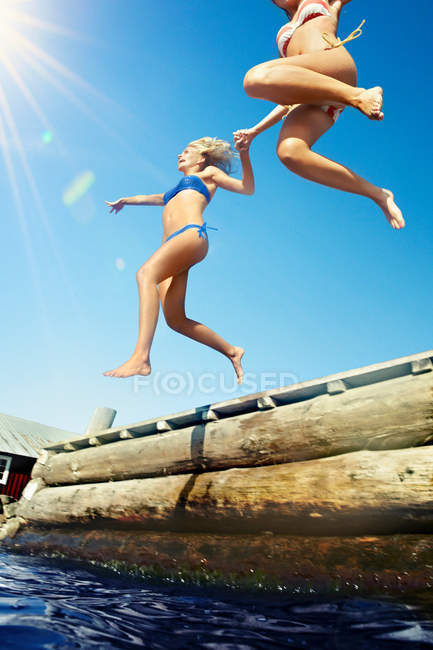 Teenage girls jumping into lake — Stock Photo