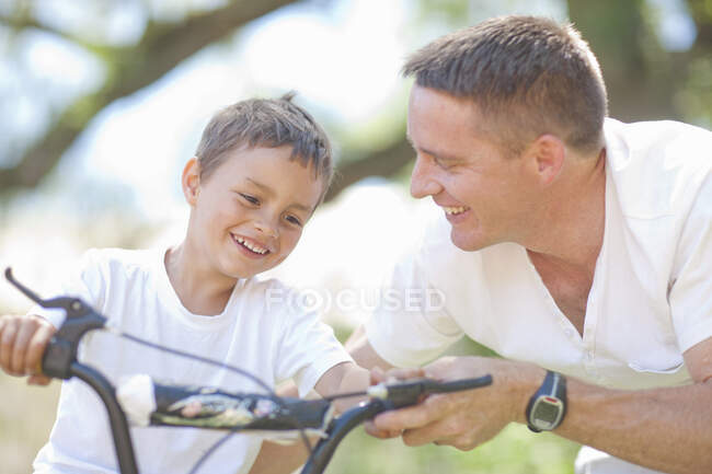 Отец ведет сына на велосипеде — стоковое фото