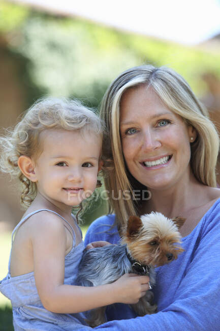 Portrait of mother holding young daughter and dog — Stock Photo