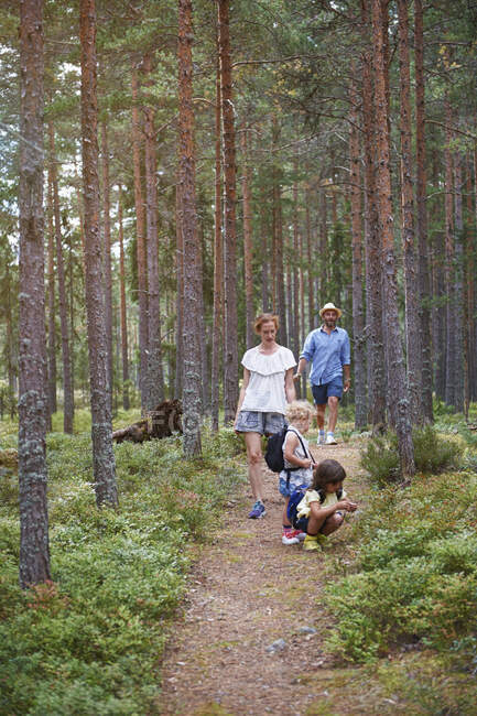 Padres caminando por el bosque con hijas - foto de stock