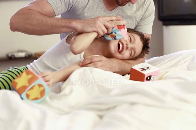 Père et petit fils jouant avec les blocs de construction sur le lit — Photo de stock