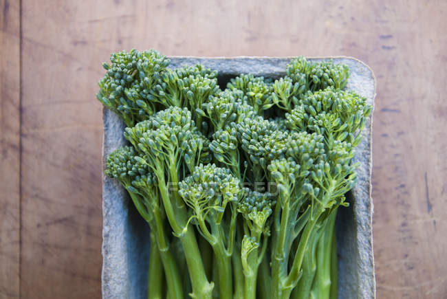 Tub of fresh broccolini on table, top view — Stock Photo
