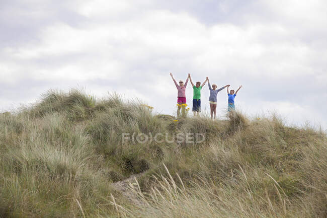 Четыре друга на дюнах с оружием в руках, Уэльс, Великобритания — стоковое фото