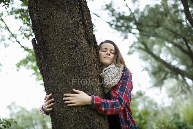 Teenage girl hugging tree in forest — Stock Photo