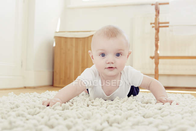 Porträt eines lächelnden Jungen, der auf Teppich kriecht — Stockfoto