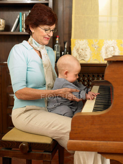 Grand-mère jouant du piano avec bébé — Photo de stock
