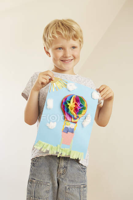 Boy holding up hot air balloon collage — Stock Photo