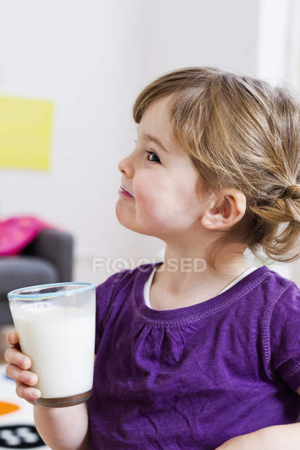 Girl holding glass of milk at home — Stock Photo