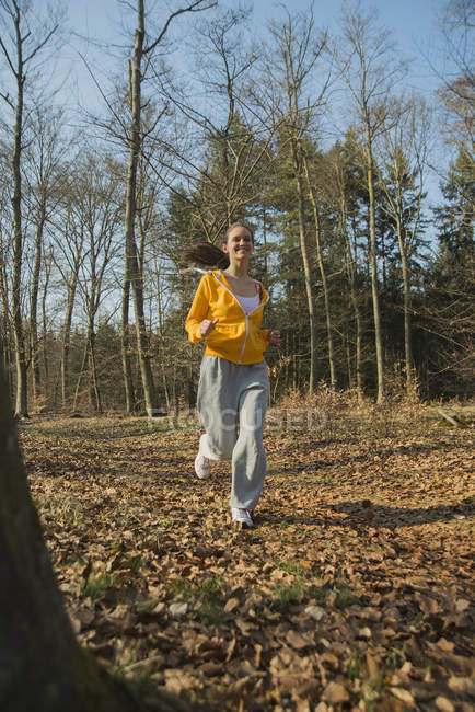 Молода жінка біжить в осінньому лісі — стокове фото