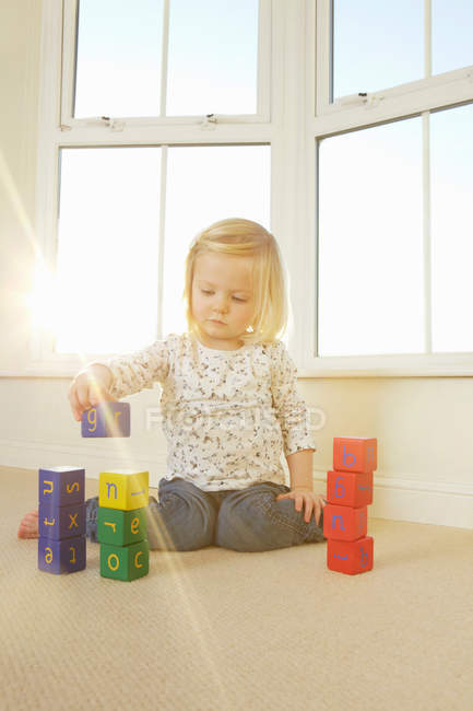 Дівчина грає з іграшковими блоками на підлозі — стокове фото