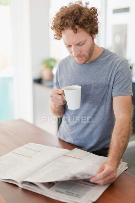 Mann liest Zeitung beim Frühstück — Stockfoto