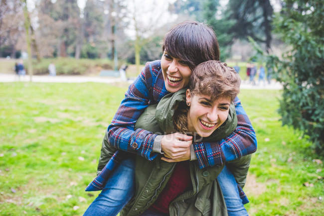 Young woman giving sister piggyback ride, outdoors — Stock Photo