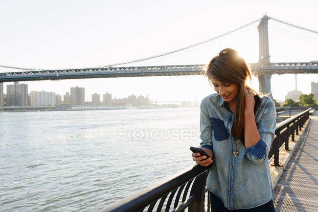 Jovem mulher usando telefone celular, Manhattan Bridge, Brooklyn, EUA — Fotografia de Stock