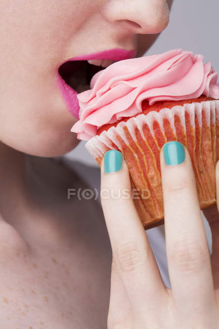 Imagen recortada de mujer joven sosteniendo cupcake - foto de stock