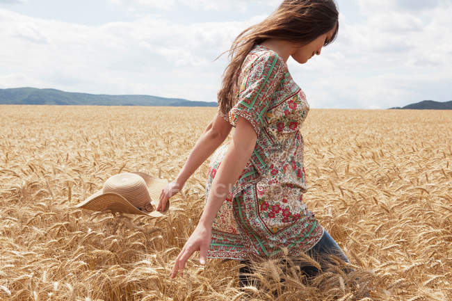Взрослая женщина идет по пшеничному полю — стоковое фото