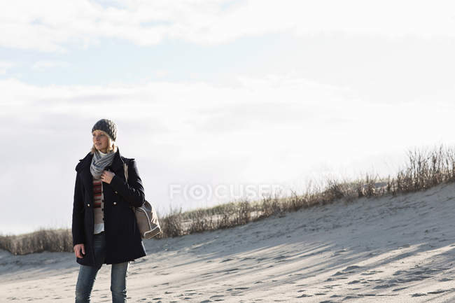 Улыбающаяся женщина стоит на пляже — стоковое фото