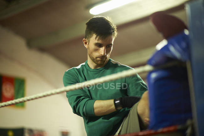 Young man exercising in boxing gym, stretching — Stock Photo