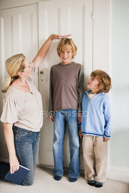 Madre midiendo a sus hijos en casa - foto de stock