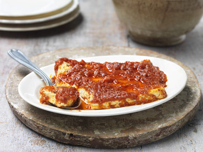 Gebackener Feta-Käse mit sonnengetrockneter Tomatensauce, in Schüssel mit Löffel — Stockfoto